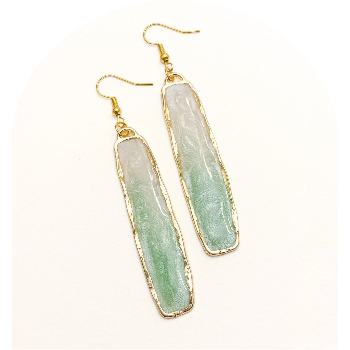 Green stone earrings with gold accents on a white background