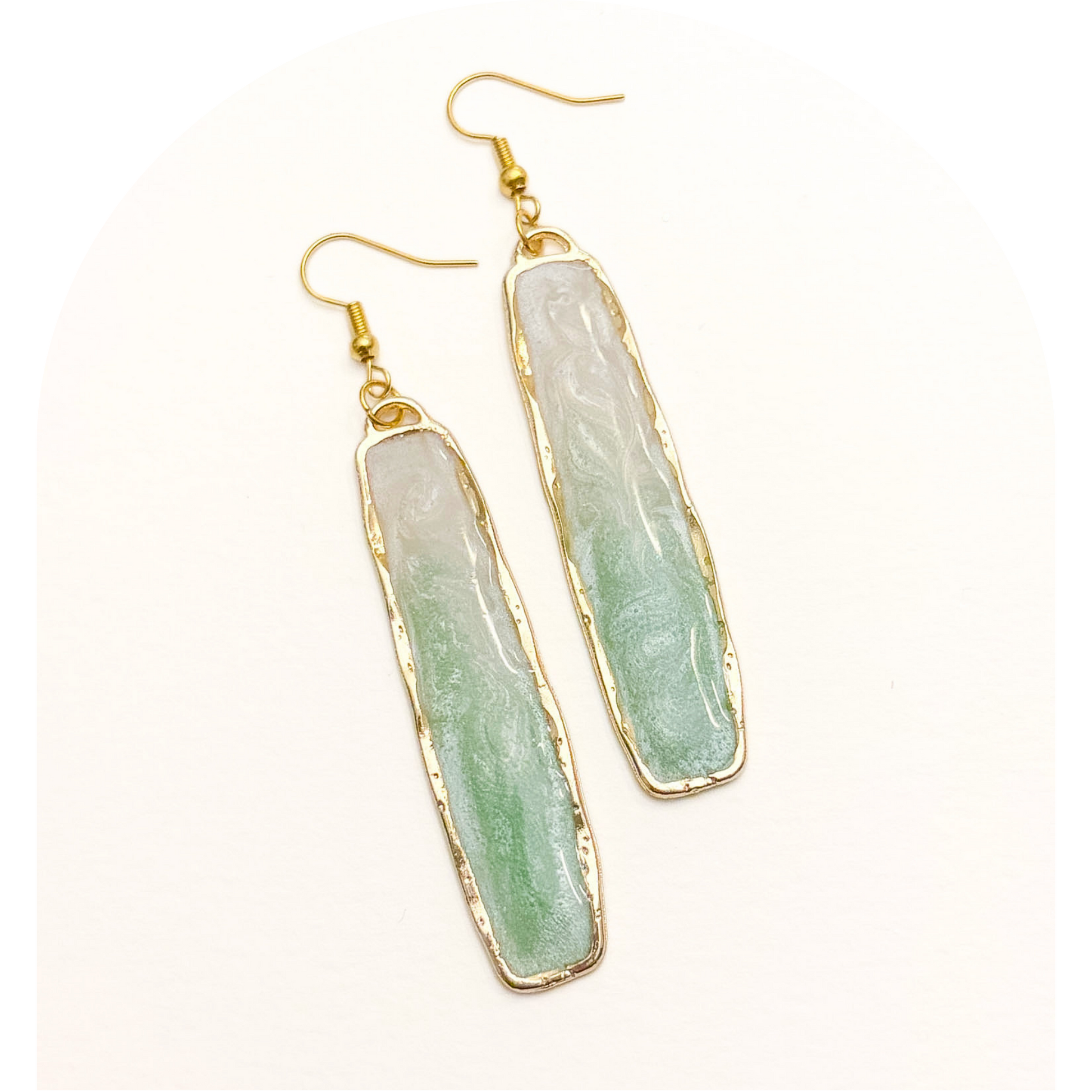 Green stone earrings with gold accents on a white background