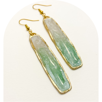 Green stone earrings with gold accents on a white background